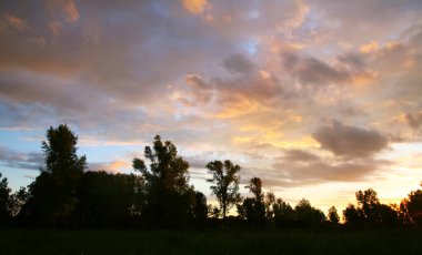 Yaz manzarası dramatik bulutlar gün batımında çayır üzerinde ve yağmurdan sonra gökkuşağı