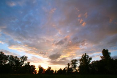 Yaz manzarası dramatik bulutlar gün batımında çayır üzerinde ve yağmurdan sonra gökkuşağı