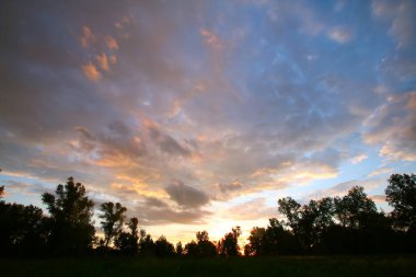Yaz manzarası dramatik bulutlar gün batımında çayır üzerinde ve yağmurdan sonra gökkuşağı