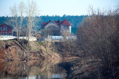 Nehir manzarası ve yaprakları olmayan ağaçlar sisli bahar sabahının erken saatlerinde