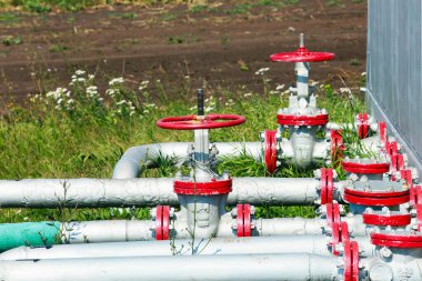 Yazın çimlerin arka planında bir tarladaki boru ve vanaların yakın plan çekimi.