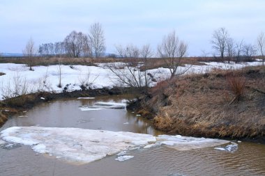 Baharın başlarında bulutlu bir günde nehir üzerindeki buz tabakası sürükleniyor.