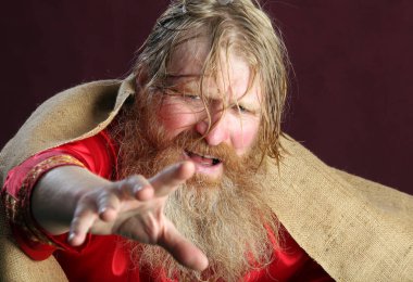 Kırmızı gömlek stüdyosunda uzun sakallı, bıyıklı ve ıslak sarı saçlı kutsanmış birinin yakın plan portresi.