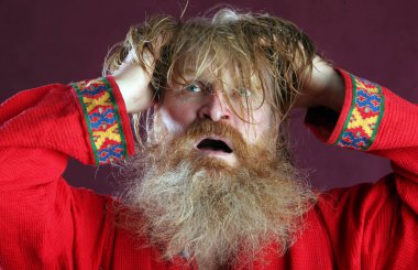 Kırmızı gömlek stüdyosunda uzun sakallı, bıyıklı ve ıslak sarı saçlı kutsanmış birinin yakın plan portresi.