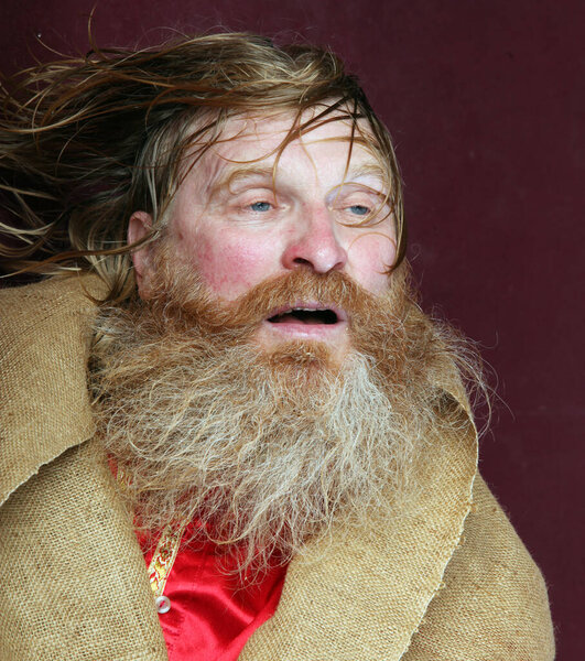 close-up portrait of the blessed with a long beard and a mustache and wet blond hair in a red shirt studio