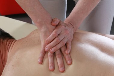 Masörün elleri izole edilmiş. Bir seans sırasında erkeğin sırtındaki kadın. Stüdyo.