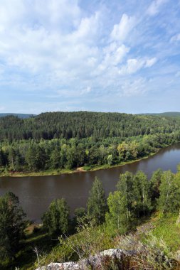 Yaz dağı manzarası Urallar 'daki İdrissova Mağarası, nehir ve orman güneşli bir günde tepeden manzara
