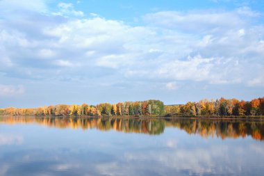 Renkli ağaçların sonbahar manzarası sakin nehrin yansıyan yüzeyine yansıyor.