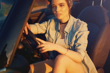 Gün batımında Cabrio 'nun arabasında oturan genç güzel kız arkadaşlarını bekle ve mükemmel bir hafta sonu düşün.