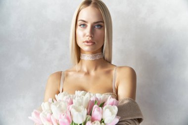 Güzel, sarışın, mavi gözlü, seksi bej iç çamaşırlı, bahar çiçekli, açık pembe ve beyaz renkli bir kadın hediye kutusunda senin için hazırlandı.