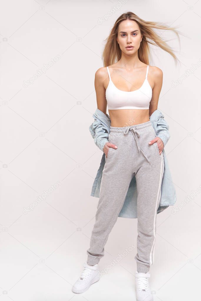 Pretty woman in sport style look with bronze skin white top and gray pants