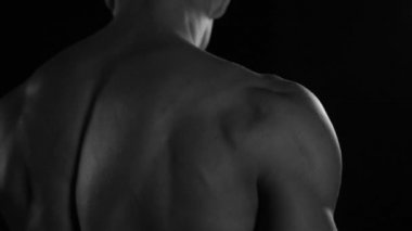 Güçlü vücut geliştirici kontrastlı ışık altında poz veriyor ve antrenman yapıyor. Vücudu ve üzerindeki tüm kasları su altında ve yavaş yağmurda gösteriyor.