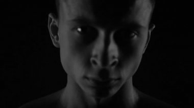 Güçlü vücut geliştirici kontrastlı ışık altında poz veriyor ve antrenman yapıyor. Vücudu ve üzerindeki tüm kasları su altında ve yavaş yağmurda gösteriyor.