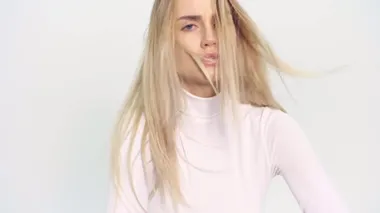 Gerçek zamanlı sinema kızı beyaz stüdyo da güzel şortlu ve rüzgarlı seksi bir şekilde poz veriyor.