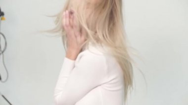 Gerçek zamanlı sinema kızı beyaz stüdyo da güzel şortlu ve rüzgarlı seksi bir şekilde poz veriyor.