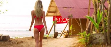 Parlak mayo giymiş güzel kız gün batımında okyanusa koşar ve Bali Adası 'nda akşam güneşine çıkar.