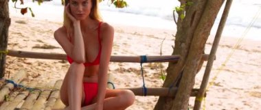 Gün batımında parlak mayo giymiş güzel bir kız Bali Adası 'nda ağaçlar ve okyanuslarla seksi pozlar veriyor.