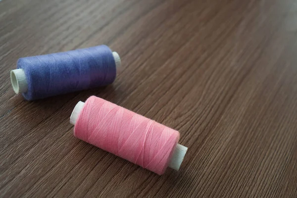 褐色桌子上的一汤匙紫色和粉色线 色彩艳丽的线线轴用于面料和纺织工业的木制桌子上 文本复制空间 裁缝店横幅模板 — 图库照片