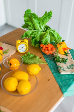 Taze yemek malzemeleri, sebze, limon ve yeşil salata arasında sarı pişirme zamanlayıcısı