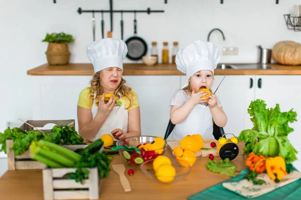 Tatlı kız masada sarı limon tadı alıyor. Çocukların vejetaryen salatası pişirmesi.