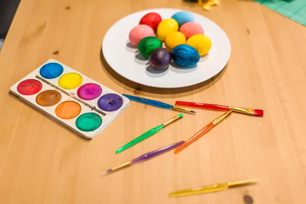 Paskalya yumurtaları ve fırçalar evdeki ahşap masada.