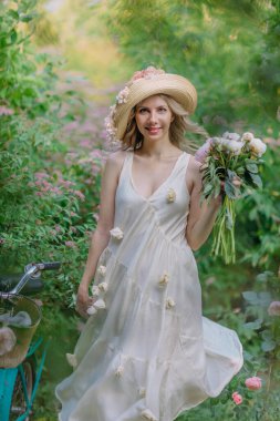 Çiçekli şapkalı ve retro elbiseli güzel bir kız bir kır evinin bahçesinde dinleniyor. Yeşil ve pembe şekerlemelerle çevrili cam bir tabakta kırmızı olgun çileklerin olduğu bir masada otururken, bir yudum su ve şakayık... 