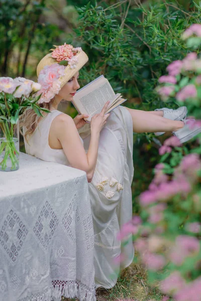 Çiçekli şapkalı ve retro elbiseli güzel bir kız bir kır evinin bahçesinde dinleniyor. Yeşil ve pembe şekerlemelerle çevrili cam bir tabakta kırmızı olgun çileklerin olduğu bir masada otururken, bir yudum su ve şakayık... 