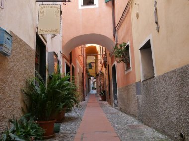 Antik Cervo köyünün tarihi merkezinde tipik bir cadde. Üzerinde renkli binalar arasındaki kemerlerle taş kaldırımlar var.