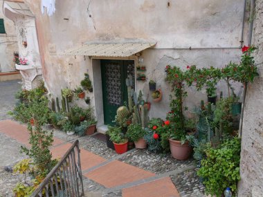 Giysileri asılmış renkli binalar ile Imperia 'nın tarihi merkezi Porto Maurizio' daki bahçeler arasında taş merdivenleri olan tipik bir cadde.