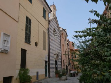 San Leonardo Kilisesi 'nin siyah beyaz çizgili cephesi. Renkli binalar ve Imperia Porto Maurizio' nun tarihi merkezinde bir duvar arasında.