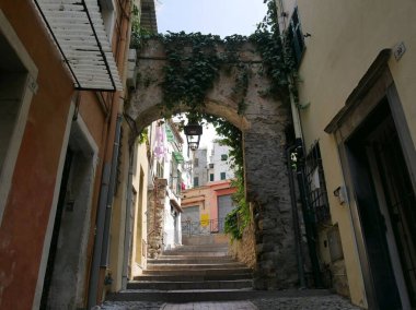 Sanremo - Pigna adında eski bir kasabada tipik bir cadde. Renkli binalar ve bahçeleri arasında kemerler var.