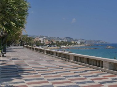 Sanremo sahil boyunca palmiye ağaçları ve beyaz-kırmızı satranç kaldırımı arasında geziniyor. 