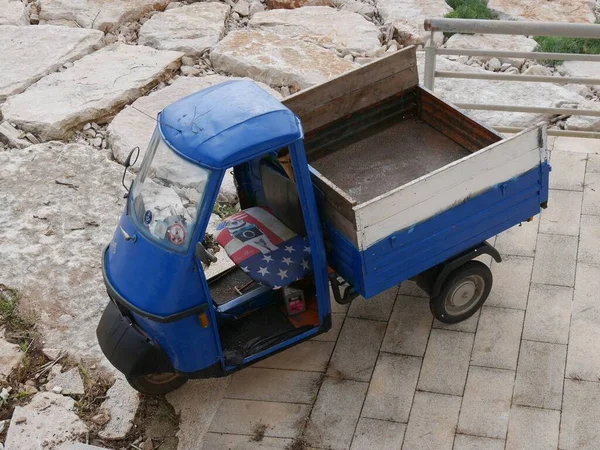 Uçurumun kenarına park edilmiş kapısı olmayan klasik mavi bir üç tekerlekli.