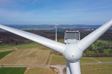 Rüzgar türbini arka planda başka bir yel değirmeniyle yaklaşıyor. Almolst 'tan çekilmiş. Almanya' nın kırsal kesimindeki merkezle aynı yükseklikte..