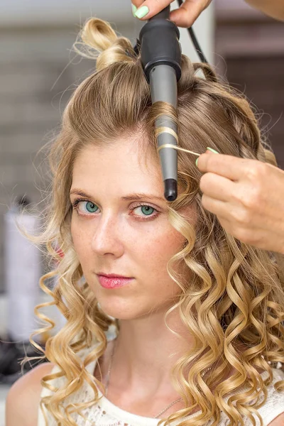 Hair stylist makes the bride before wedding