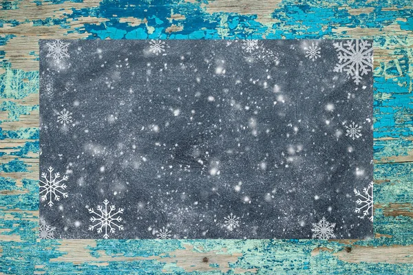 Placa de giz com flocos de neve em uma superfície rústica — Fotografia de Stock