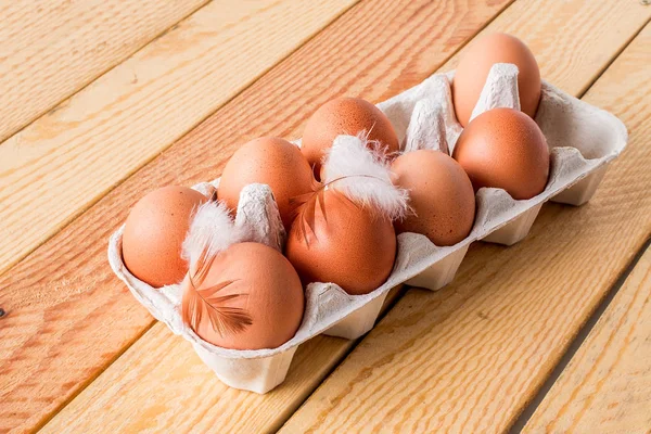 Acht eieren in vak op een houten tafel — Stockfoto