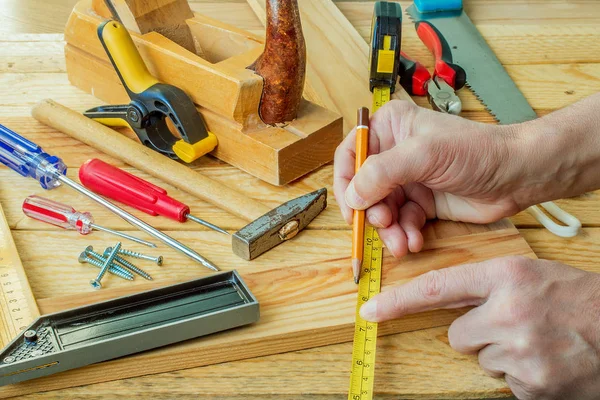 Mano de hombre trabajando en el escritorio del carpintero y herramientas de trabajo —  Fotos de Stock