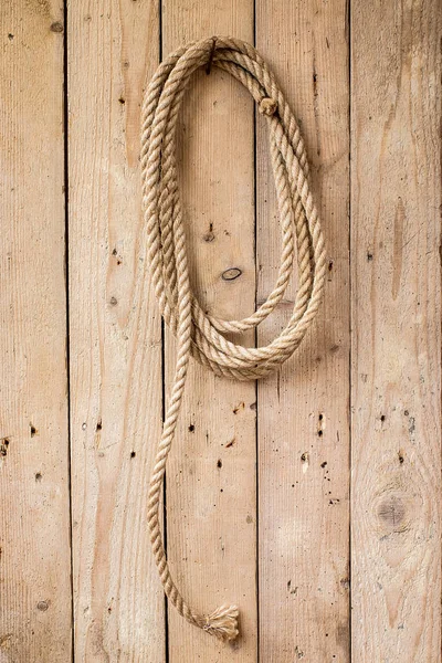 Corda marrom pendurada na parede de madeira — Fotografia de Stock