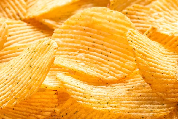 Yellow salted potato chips as background, closeup