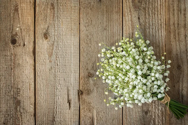 Lys de la vallée dans un bouquet sur une vieille table en bois — Photo