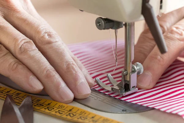 Handen op naaimachine houden sommige stof — Stockfoto