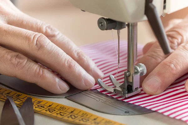 Handen op naaimachine houden sommige stof — Stockfoto