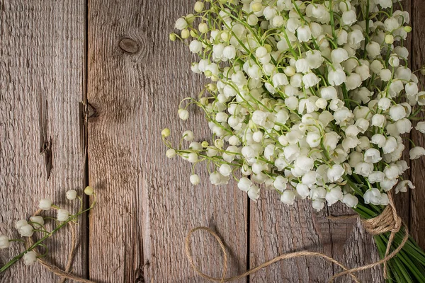 Lilly de vallée dans un vase en verre sur une table en bois — Photo