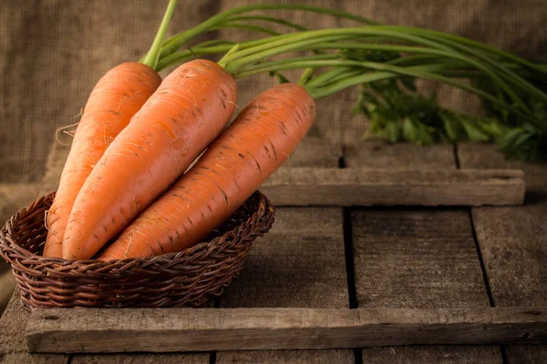 Verse biologische wortelen in een mand op houten achtergrond — Stockfoto