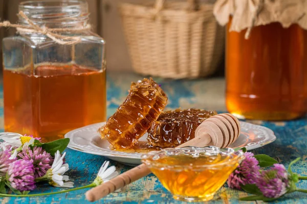 Twee honing potten met honingraat op een houten tafel met bloemen — Stockfoto