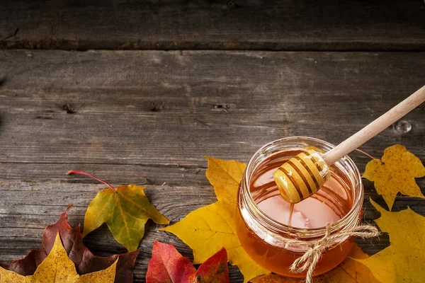 Το μέλι και το φθινόπωρο τα φύλλα σε ένα ξύλινο τραπέζι — Φωτογραφία Αρχείου