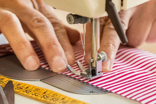 Handen op naaimachine houden sommige stof — Stockfoto