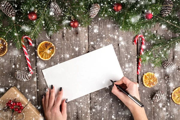 Female hand writing a letter to Santa on wooden background — Stock Photo, Image