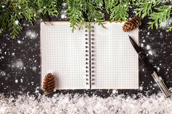 Adornos navideños y un cuaderno abierto en blanco sobre una pizarra — Foto de Stock